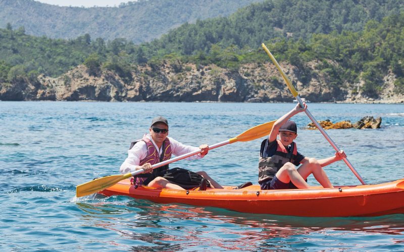 Boat kayaking near cliffs on a sunny day. Kayaking in a quiet bay. Amazing views. Travel, sports concept. Lifestyle. A happy family